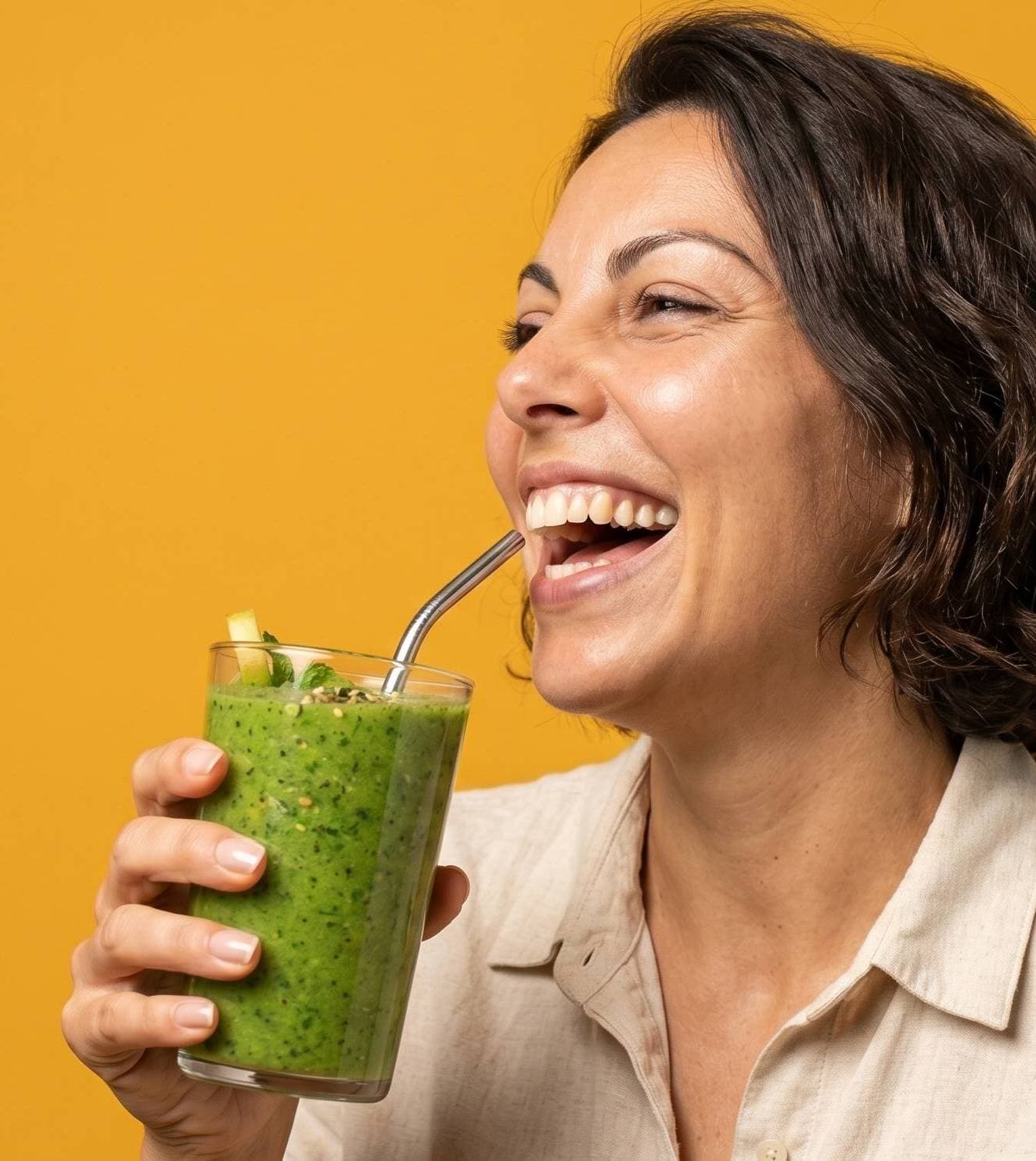 Pessoa sorrindo enquanto bebe um suco verde
